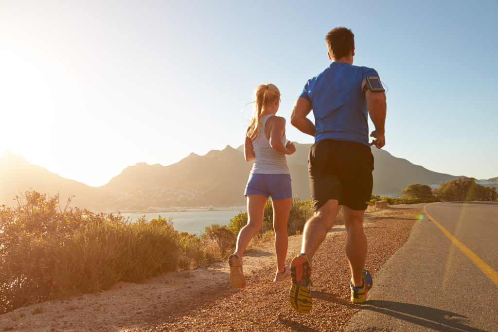 Man and woman running together on an empty road